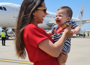 Mãe entrando no avião com bebê no colo para viagem com um bebê