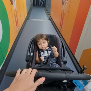 Bebê de 1 a 2 anos no carrinho entrando no corredor de embarque do avião