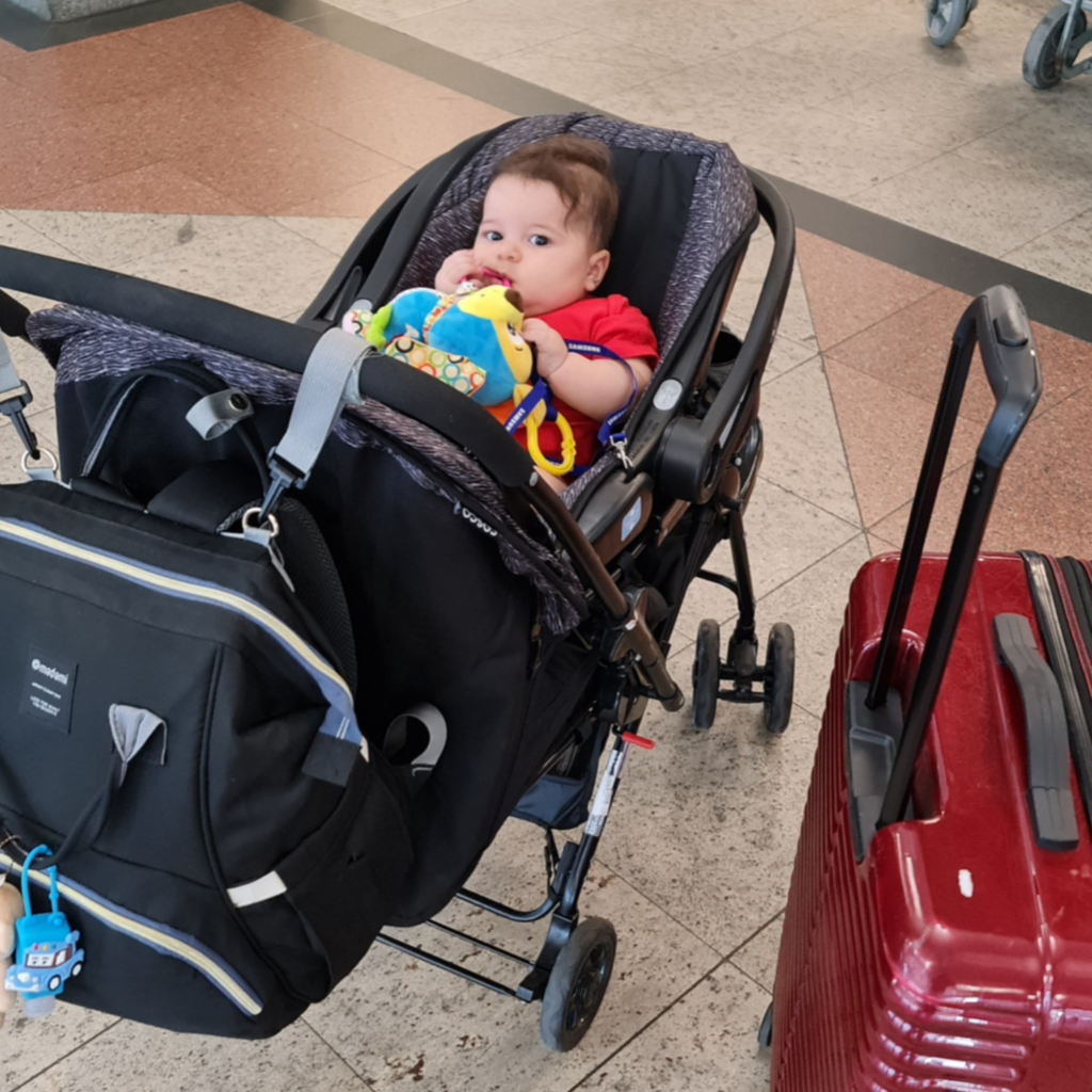 Bebê de até 6 meses no carrinho com bebê conforto ao lado das malas